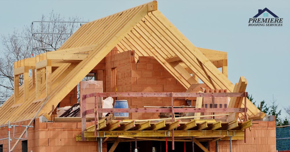 Newly framed roof structure on a brick building under construction with scaffolding.