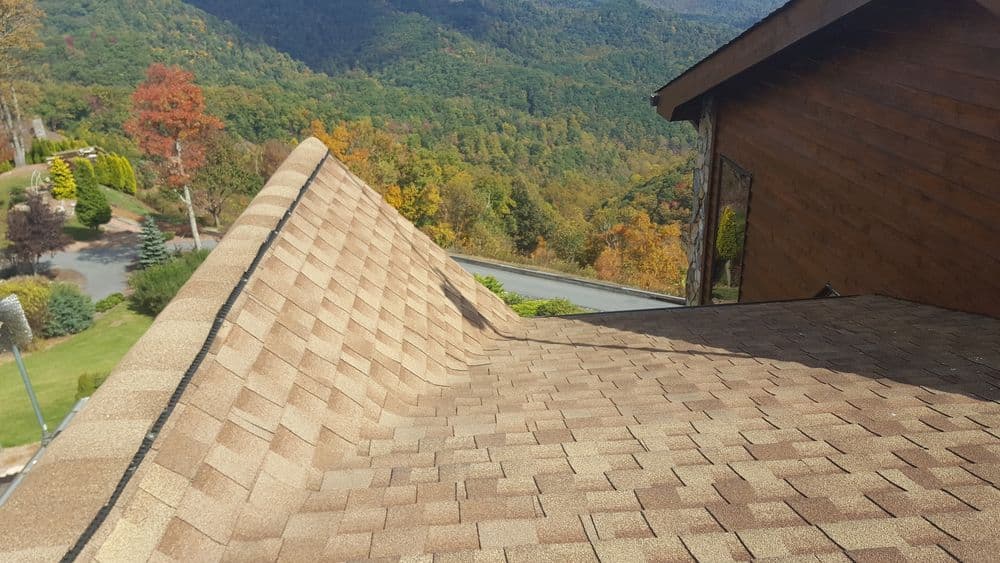 Overhead view of a shingled roof with autumn landscape and mountains in the background.