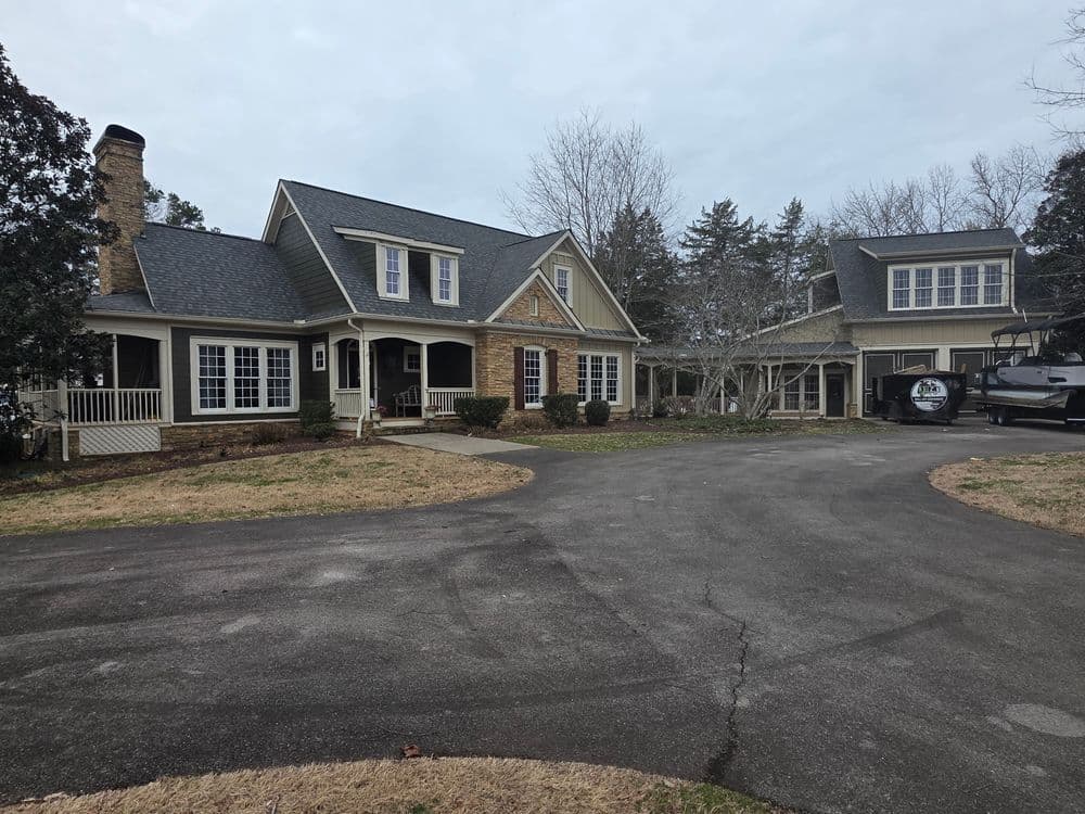 Spacious two-story home with stone accents and circular driveway surrounded by trees.