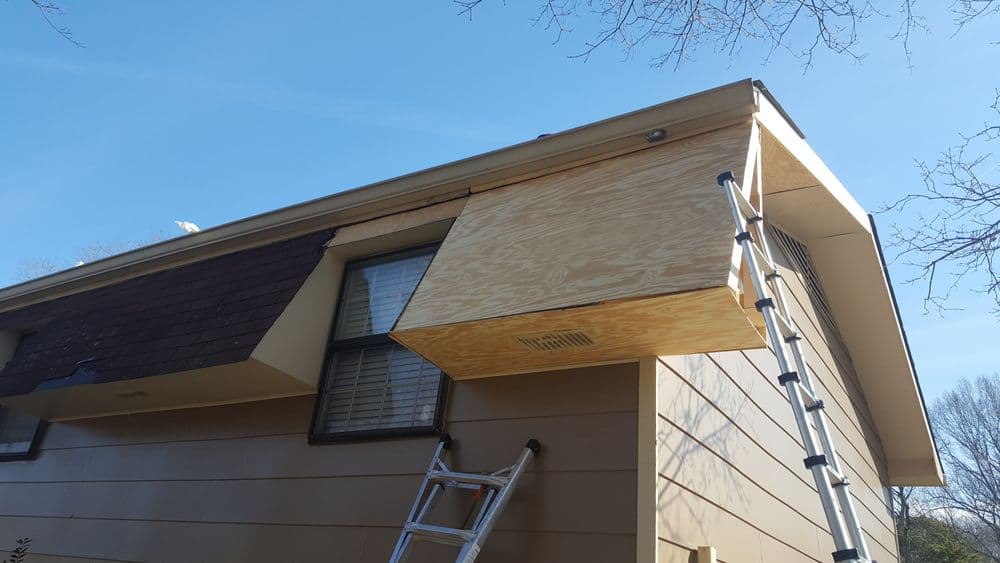 Exterior view of a house with a wooden structure under construction and a ladder nearby.