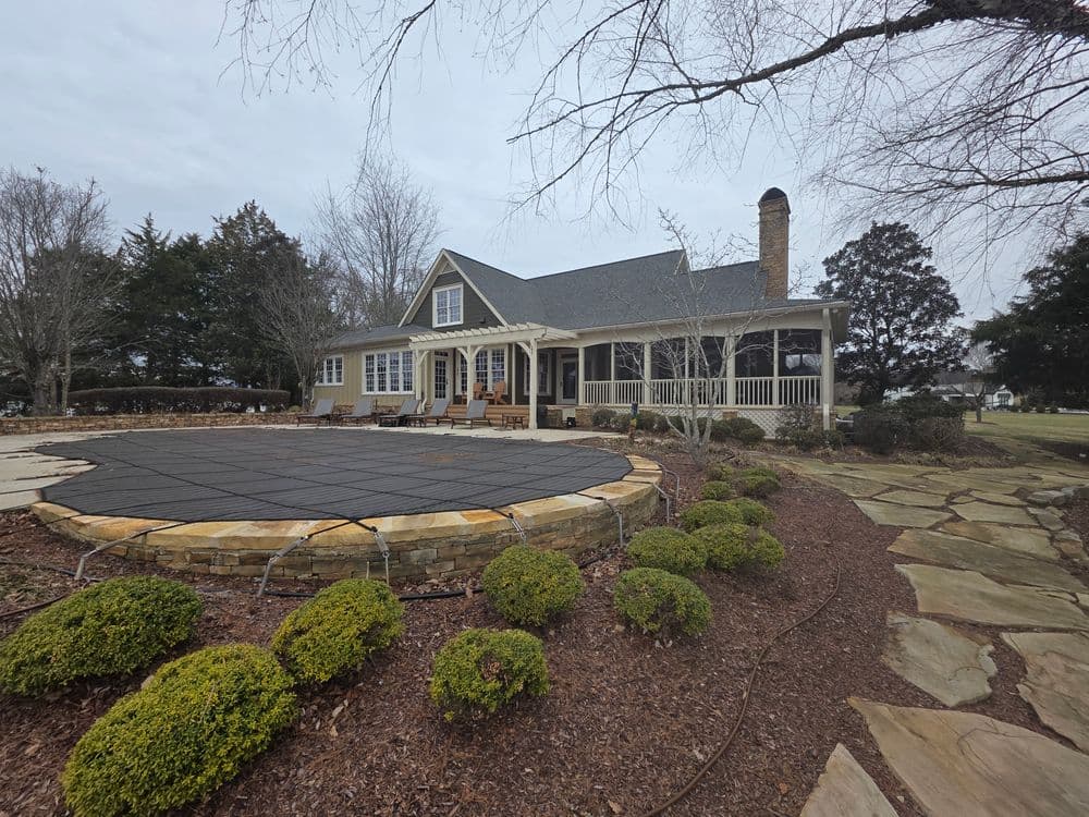 Charming home with a wraparound porch, surrounded by landscaped yard and a covered pool.